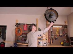 a man is holding up a fan in his garage