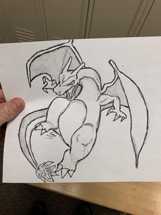 a person holding up a drawing of a dragon