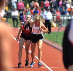 two women running on a track with people watching