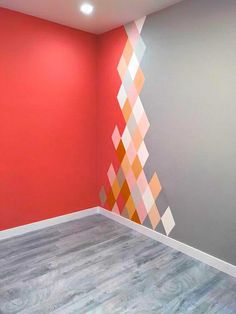 an empty room with red walls and white trim on the wall is decorated with geometric shapes