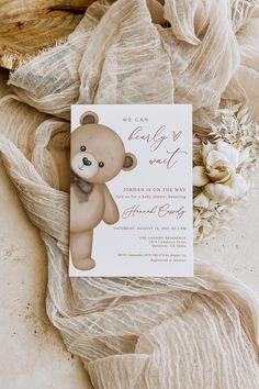 a card with a teddy bear on it sitting next to some flowers and fabric material