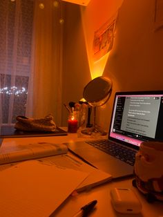 an open laptop computer sitting on top of a desk next to a cup and pen