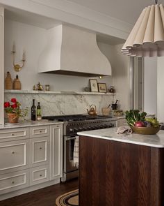 a kitchen with white cabinets and an island in front of a stove top oven that is surrounded by potted plants