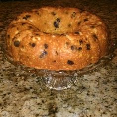 a loaf of bread sitting on top of a glass cake plate in front of a granite counter