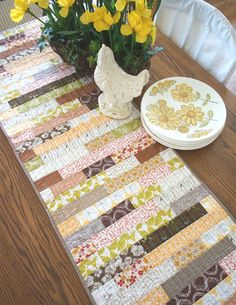 a table runner with yellow flowers in a vase next to a plate on the table