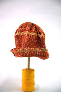 "A cheerful way to get through winter!  This lightweight one of a kind hat can be worn year round.  It is handwoven with a variety of fibers. The main body is orange, but it contains yellow, greens, browns, lilacs and metallic yarns.  One size fits many.  It measures 27 cm from top to brim, with a 4 cm (1.5 inch) brim, it has a circumference of 63.5 cm at the brim.  Hand wash.  Please note - colors may vary from photo. Allow for slight variations in color as their appearance may differ from scre Orange Winter Hat With Short Brim, Winter Orange Hat With Short Brim, Orange Bohemian Hat With Curved Brim, Orange Wide Brim Hat For Winter, Orange Wide Brim Winter Hat, Handmade Beach Hat For Fall, Fitted Orange Casual Hat, Fitted Casual Orange Hat, Spring Brown Knitted Hats