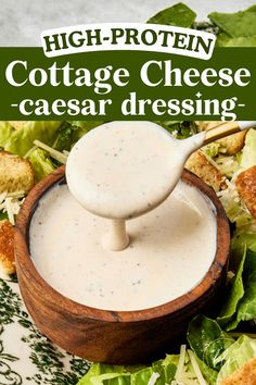 a wooden bowl filled with cheese dressing next to lettuce and croutons