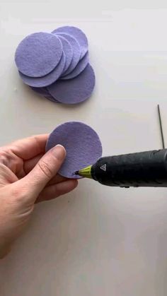 someone is cutting out purple felt circles on a table