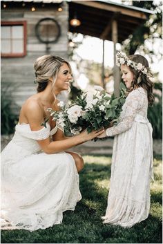 two women in white dresses are holding flowers and one is kneeling down with her hand on another woman's shoulder