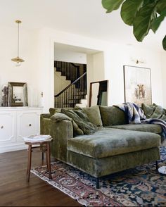 a living room filled with furniture next to a stair case in a white walled house