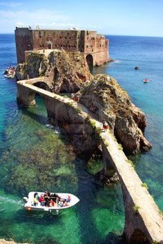 people are on a boat in the water near an old stone bridge that is connected to a castle