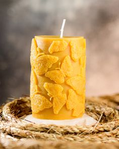 a yellow candle sitting on top of a pile of hay