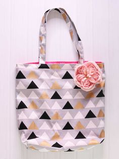 a pink flower sitting on top of a white and black bag with geometric pattern design