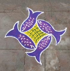 a painted fish design on the ground with purple, yellow and white colors in it