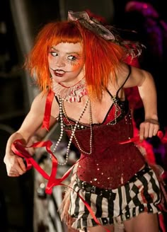 a woman with red hair and makeup is dressed as a clown