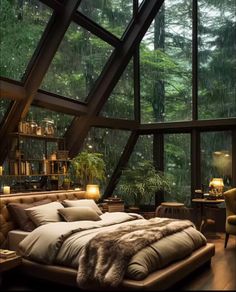 a large bed sitting under a window next to a forest filled with lots of trees