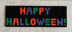 a sign that says happy halloween on the side of a building with words written in multicolored letters