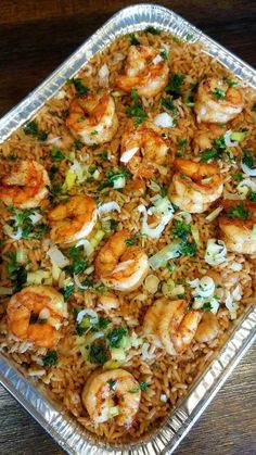 a pan filled with shrimp and rice on top of a wooden table