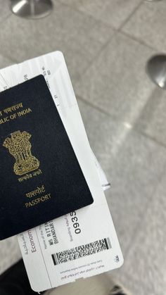 a passport is held up by someone's hand in front of some silver plates