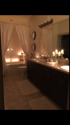 a large bathroom with candles on the wall and two sinks in front of the tub