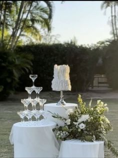 two white candlesticks sitting on top of a table covered in flowers and greenery