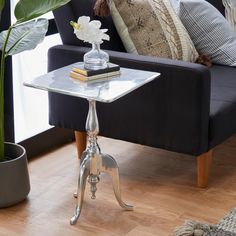 a living room with a couch, table and potted plant on the floor next to it