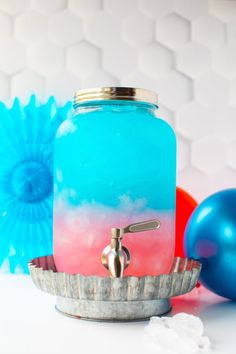 a blue and red drink sitting on top of a metal tray next to balloons in the background