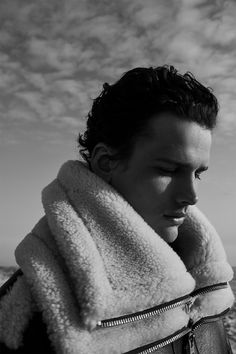 black and white photograph of a man wrapped in a towel looking out at the ocean