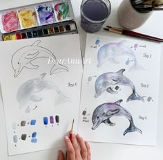 someone is painting dolphins on paper with watercolors and crayon pencils