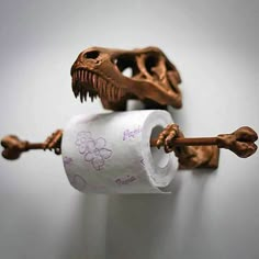 a dinosaur toothbrush holder is holding two rolls of toilet paper