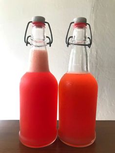 two bottles filled with liquid sitting on top of a wooden table