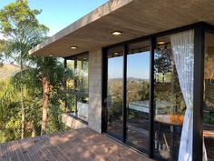 an outdoor deck with sliding glass doors leading out to the trees and mountains in the distance