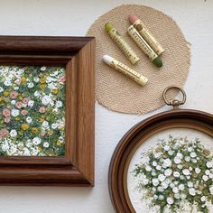 a wooden frame sitting on top of a table next to a painting and some crayons