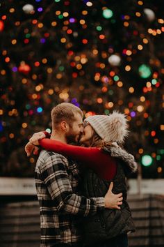 a man and woman hugging in front of a christmas tree