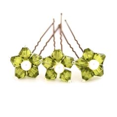 four green flowers with pearls on them are hanging from the back of some hair pins