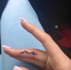 a woman's hand with a small wave tattoo on her left thumb and the word love written in black ink