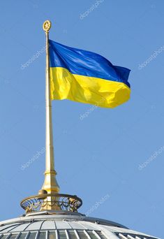 the flag of ukraine flying on top of a building with a blue sky in the background