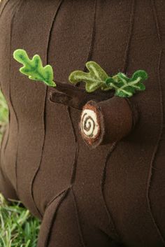 a stuffed animal that is sitting in the grass with leaves on it's back