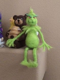 three stuffed animals sitting on top of a white shelf next to each other in front of a wall