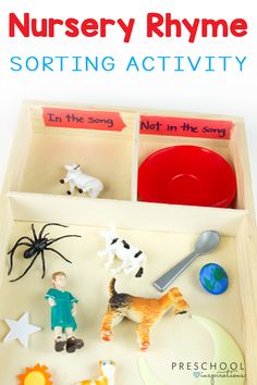 a wooden tray with toy animals and toys in it that says nursery rhyme sorting activity