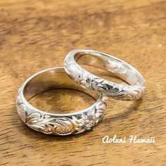 two silver wedding rings sitting on top of a wooden table next to each other,