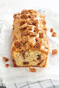 a loaf of cake covered in frosting and pretzels on top of wax paper