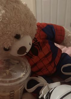 a teddy bear sitting on top of a bed next to a plastic container