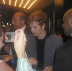 a young man is taking a photo with his cell phone while people are around him