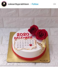 a white cake decorated with red roses and a calendar on the side that says, 2020 december