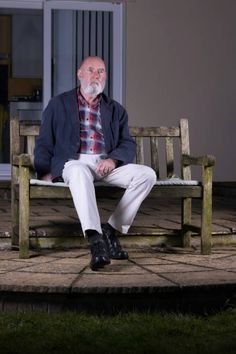 an older man sitting on a wooden bench