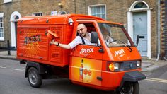 a man driving an orange truck down the street