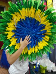 a person holding up a large colorful piece of art made out of plastic straws