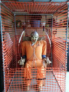 a man in an orange prison outfit sitting in a cage