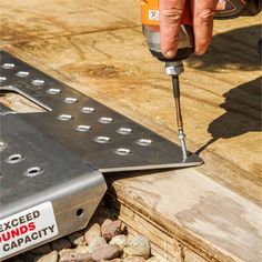 a person using a drill to fix a piece of metal on top of a wooden table